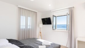 Camera d'albergo moderna con un letto, una TV a parete, una finestra vista e un comodino.