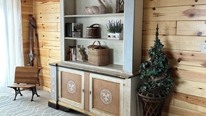 A wooden-paneled room with a vintage-style cabinet, a bench, and a small Christmas tree.