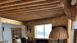 A cozy cabin interior with a sofa, chairs, a TV, and a lamp.