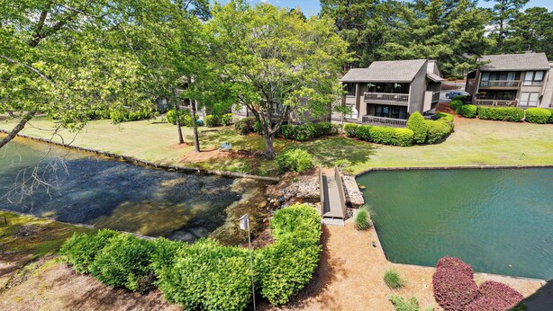 A residential area with a pond, a wooden bridge, and two buildings with balconies. - Lakefront Pinehurst Condo 2BD/2BA - 237 - With Community Pool Access (Pinehurst)