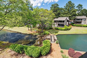 A residential area with a pond, a wooden bridge, and two buildings with balconies. - Lakefront Pinehurst Condo 2BD/2BA - 237 - With Community Pool Access (Pinehurst)
