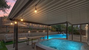 Une terrasse extérieure dotée d’un jacuzzi, d’un espace salon et de guirlandes lumineuses.