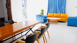 A modern living room with a wooden dining table, blue sofas, and a small coffee table.