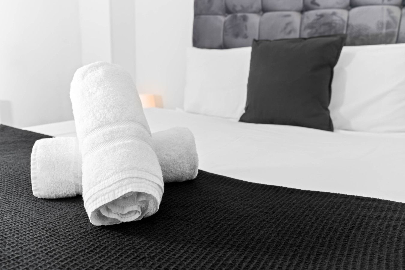 Una cama bien hecha con sábanas blancas y un cabecero oscuro.