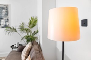 A modern living room with a floor lamp, a sofa, and a potted plant. - Modern 3 Bedroom Townhouse - Bedroom TVs - Wolverhampton Centre (Wolverhampton)