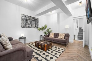 A modern living room with a grey sofa, a patterned rug, a vintage trunk, and a large abstract painting on the wall. - Modern 3 Bedroom Townhouse - Bedroom TVs - Wolverhampton Centre (Wolverhampton)