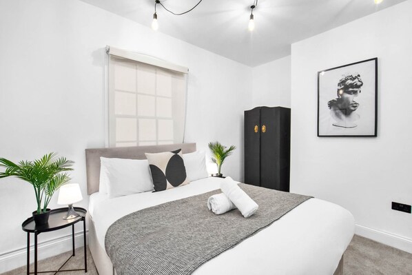 Un dormitorio moderno con cama, mesita de noche, lámpara, planta en maceta y armario.