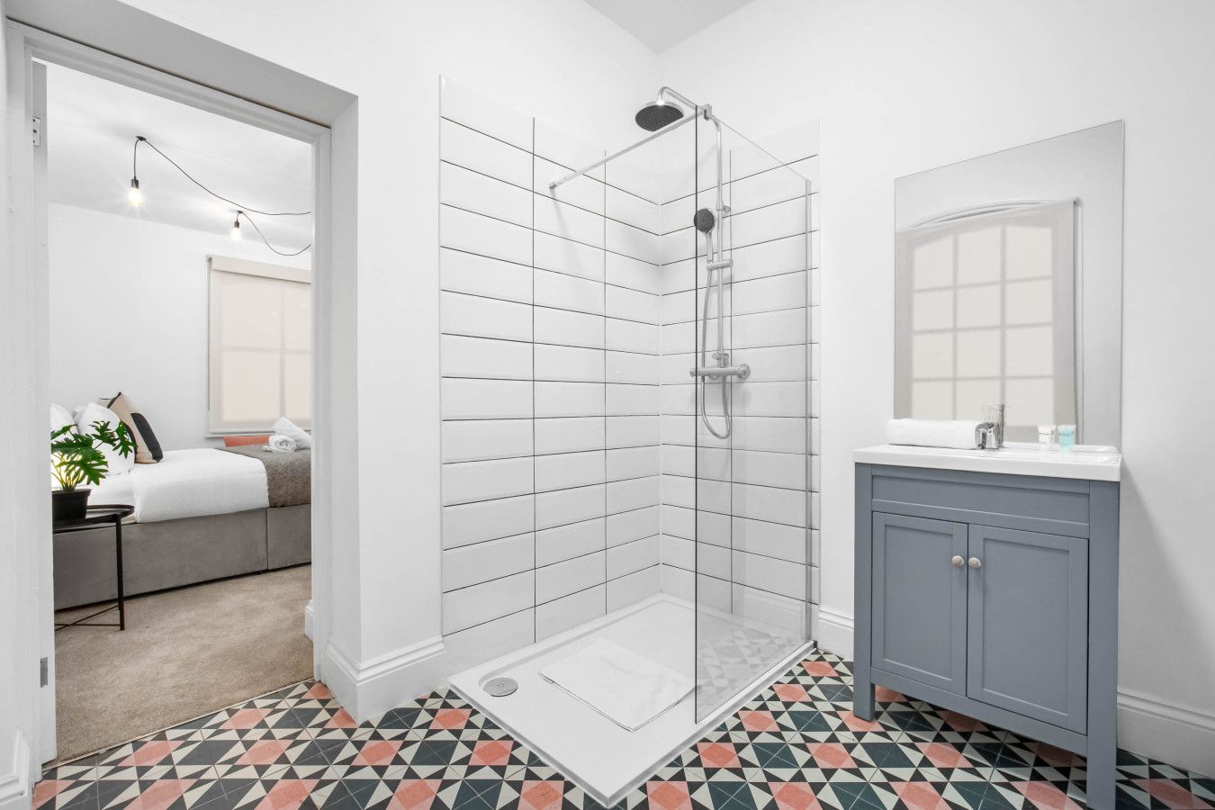 Un baño moderno con ducha, lavamanos y espejo.