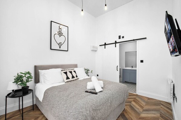 A modern bedroom with a bed, bedside table, and a wall-mounted TV.