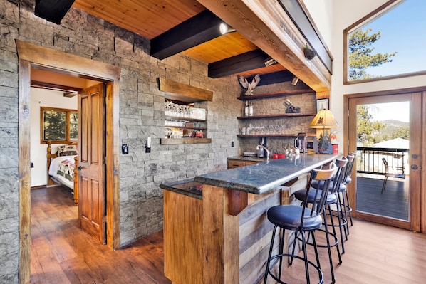 Una cocina rústica con pared de piedra, vigas de madera y una zona de bar con taburetes.