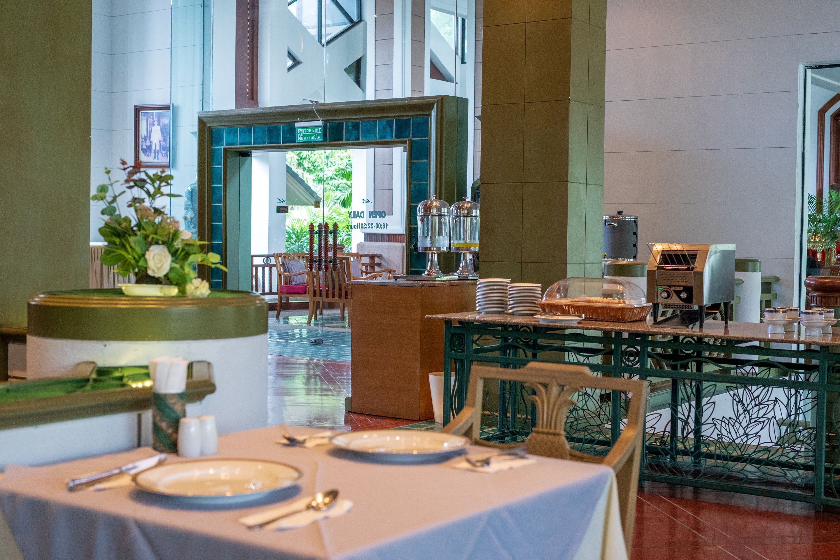A hotel lobby with a reception desk, a buffet area, and a seating area with tables and chairs.
