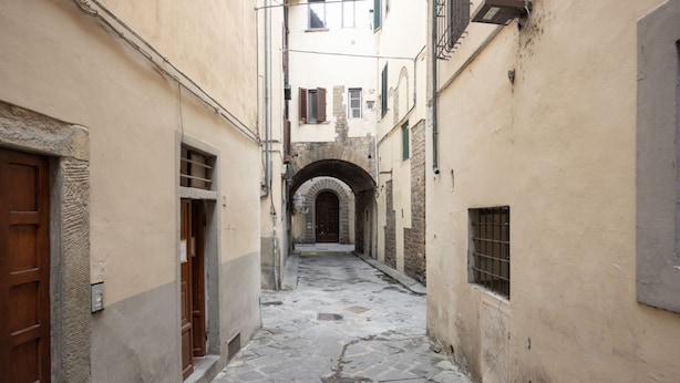 A narrow stone-paved alleyway between buildings with arched doorways and wooden doors. - Tornabuoni Dream By MMega (Firenze)