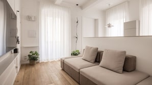 A modern living room with a sofa, a television, and a plant. - Tornabuoni Dream By MMega (Firenze)
