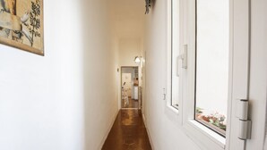 Un passadís amb un sòl hexagonal marró, parets blanques i una porta amb finestre.