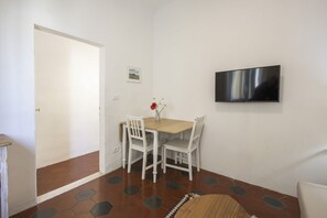 Una habitación con una mesa de comedor, sillas, un televisor y una puerta.