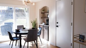 A dining area with a round table, chairs, and a chandelier. There is a kitchen area with shelves and a door. - Spacious 4BR Home+Patio Retreat (Centennial)
