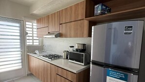Une cuisine moderne avec des meubles en bois, un réfrigérateur en acier inoxydable et une cuisinière à gaz.