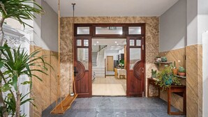 A hotel entrance with a marble wall, a wooden door, and a staircase leading to the upper floor.