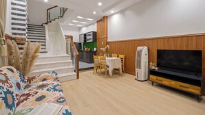 A modern living room with a staircase, a dining area, and a TV stand.