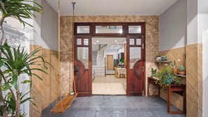 A hotel entrance with a marble floor, wooden doors, and potted plants.
