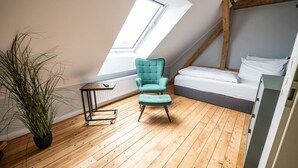 A room with a sloped ceiling, a bed, a teal chair, a small table, and a potted plant. - 6 rooms 5 bedrooms 2 bathrooms- close to the city center top renovated (Brunsbüttel)