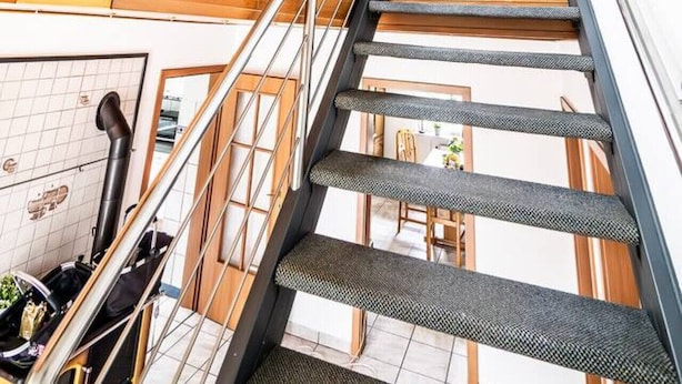 A modern interior with a staircase leading to an upper level, large windows, and a visible kitchen area. - Beautiful house with conservatory and garden and large bathrooms (Brunsbüttel)
