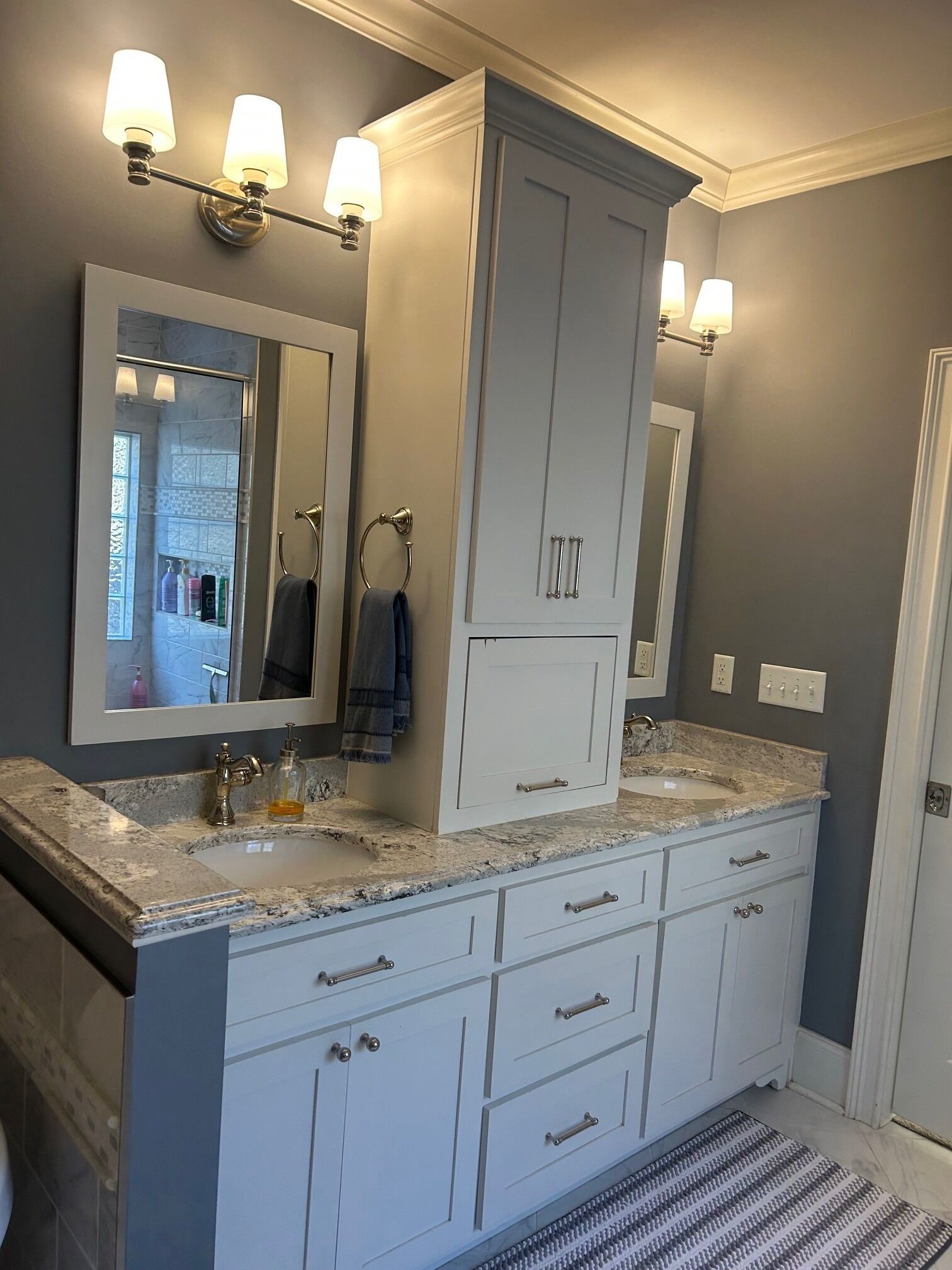 A modern bathroom with a large mirror, two sinks, and a walk-in shower.