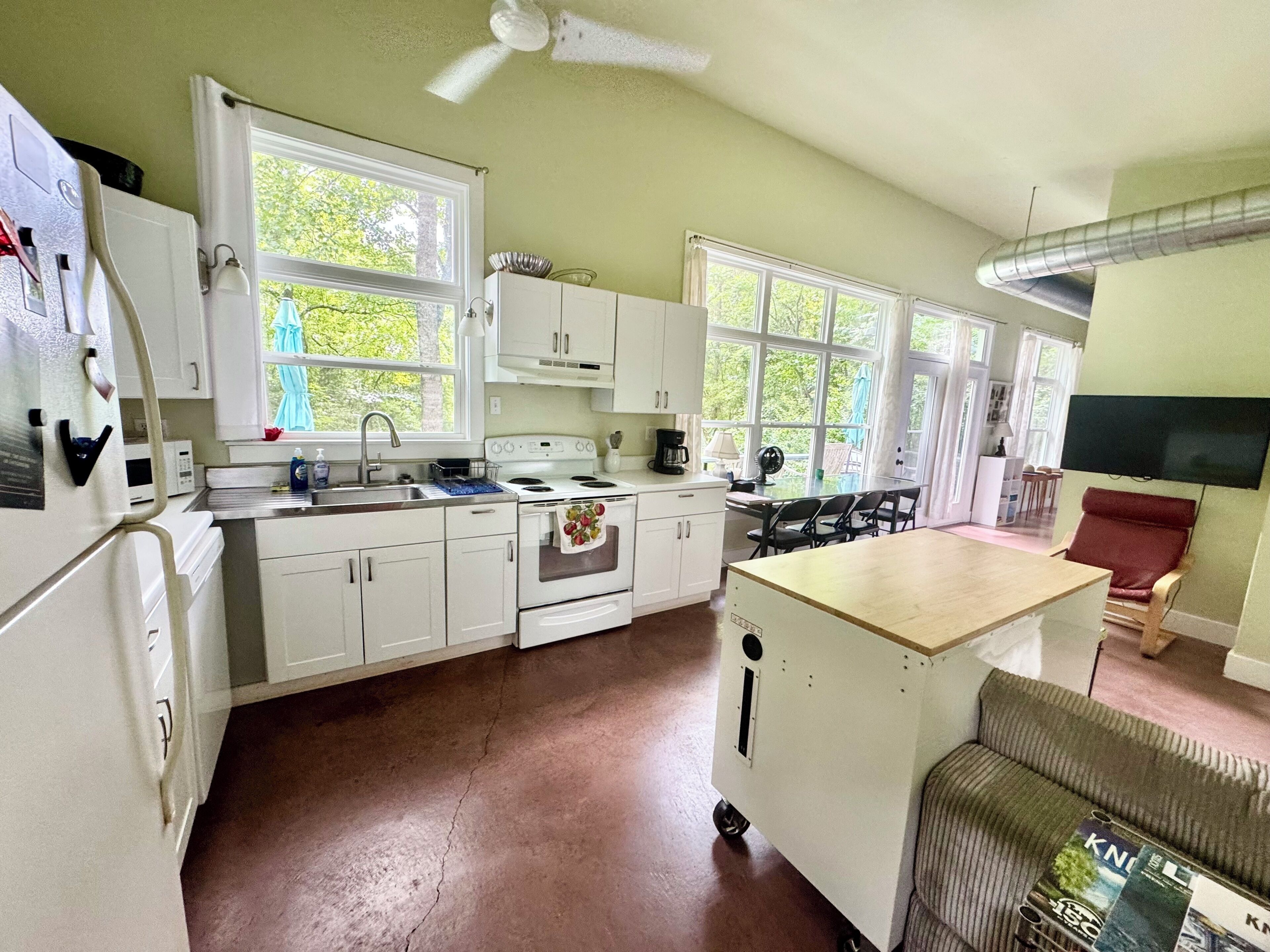 A kitchen with white cabinets, a stove, and a dining area with a table and chairs.