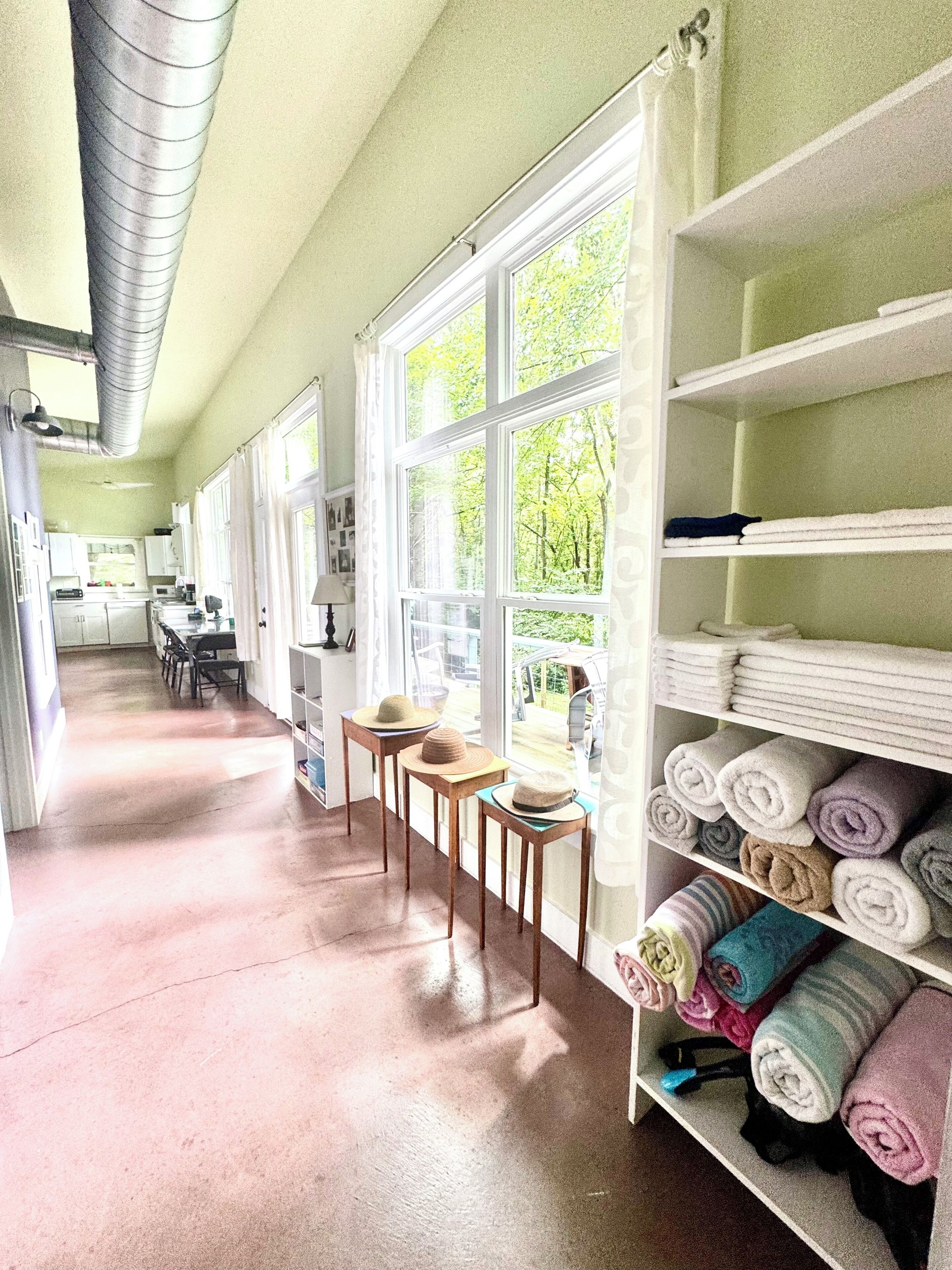 Tilava keittiö, josta on näkymä vehreään maisemaan, ruokailutila tuoleineen sekä hylly, jossa on siististi rullalle taitetut pyyhkeet.