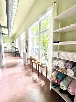 Een ruime keuken met uitzicht op groen, een eethoek met stoelen en een plank met netjes opgerolde handdoeken.
