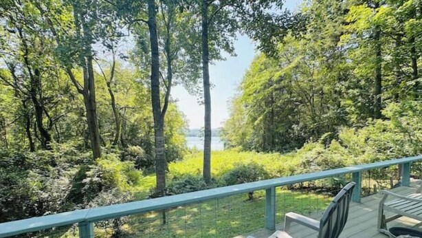 Eine Terrasse mit Blick auf einen Wald und ein Gewässer.