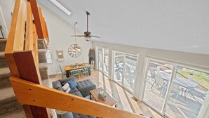 A spacious living area with a wooden staircase, a gray sofa, and a dining table. - "High Rock Haven- Fire Pit, Welcome Gifts,  Games room, Hot Tub, 2 lounges, lake (Lexington)