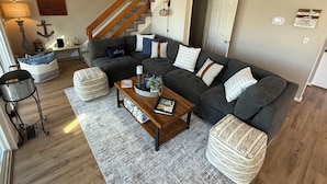 A living room with a dark grey sectional sofa, a wooden coffee table, and a grey patterned rug. - "High Rock Haven- Fire Pit, Welcome Gifts,  Games room, Hot Tub, 2 lounges, lake (Lexington)