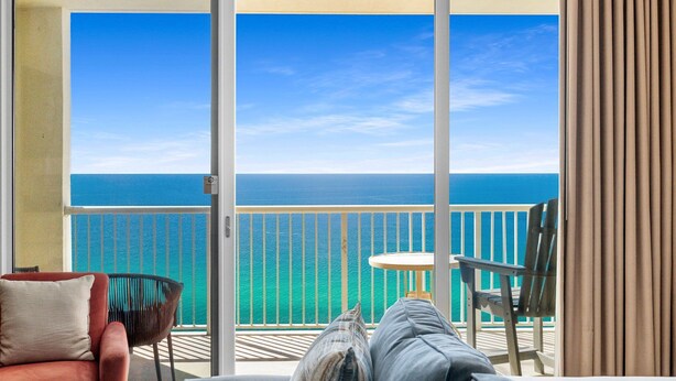 Ein Balkon mit Blick auf das Meer, ein Sessel, ein Tisch und eine Couch.