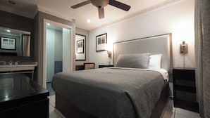 A hotel room with a bed, a ceiling fan, a nightstand, a mirror, and a bathroom area. - Hotel Tj Plaza (Tijuana)