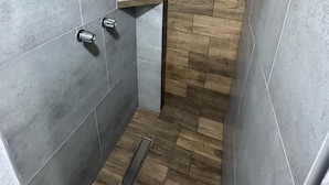 A narrow shower area with grey tiles and a wooden floor. - Hotel Tj Plaza (Tijuana)