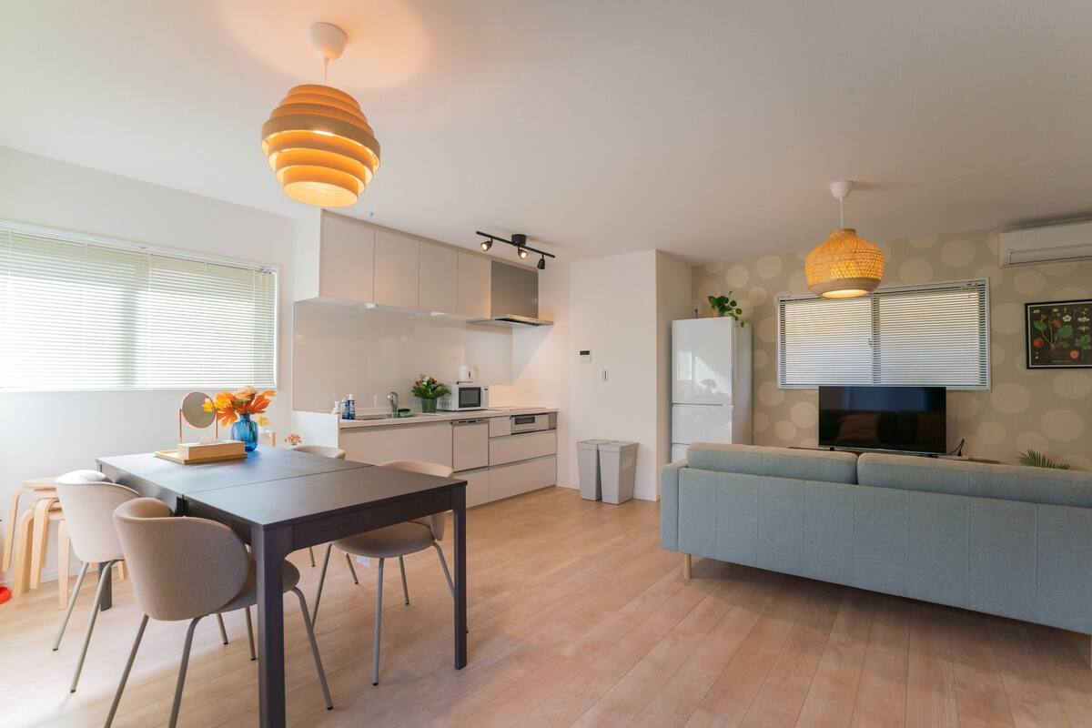 A modern kitchen with a dining area, a sofa, and a TV.