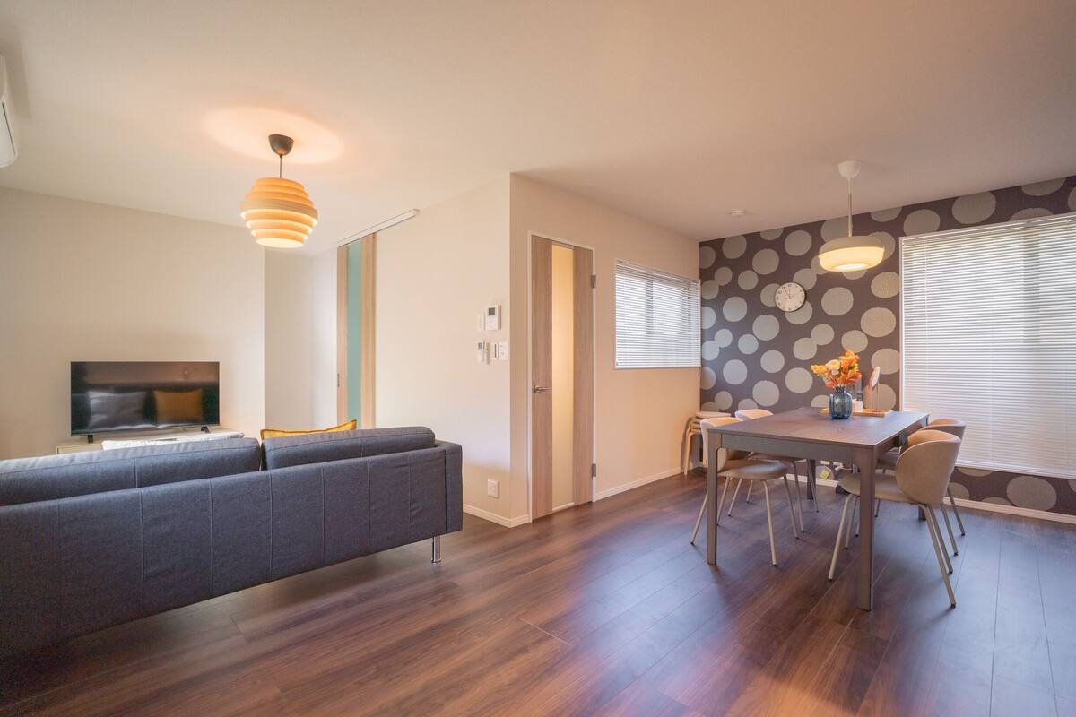 A modern living room with a sofa, TV, and dining area with a table and chairs.