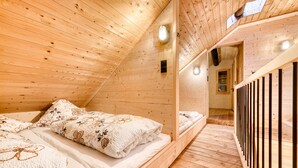Un dormitorio de cabaña de madera con techo inclinado, una cama con ropa de cama floral y suelo de madera.