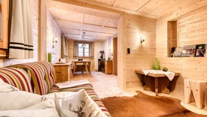 Acogedor interior de cabaña de madera con sofá, una mesa de comedor y una pequeña cocina.