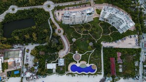 Vue aérienne d’un complexe hôtelier comprenant une grande piscine, plusieurs bâtiments et un parking.