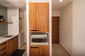Una cocina compacta con armarios de madera, microondas integrado y cafetera sobre la encimera.