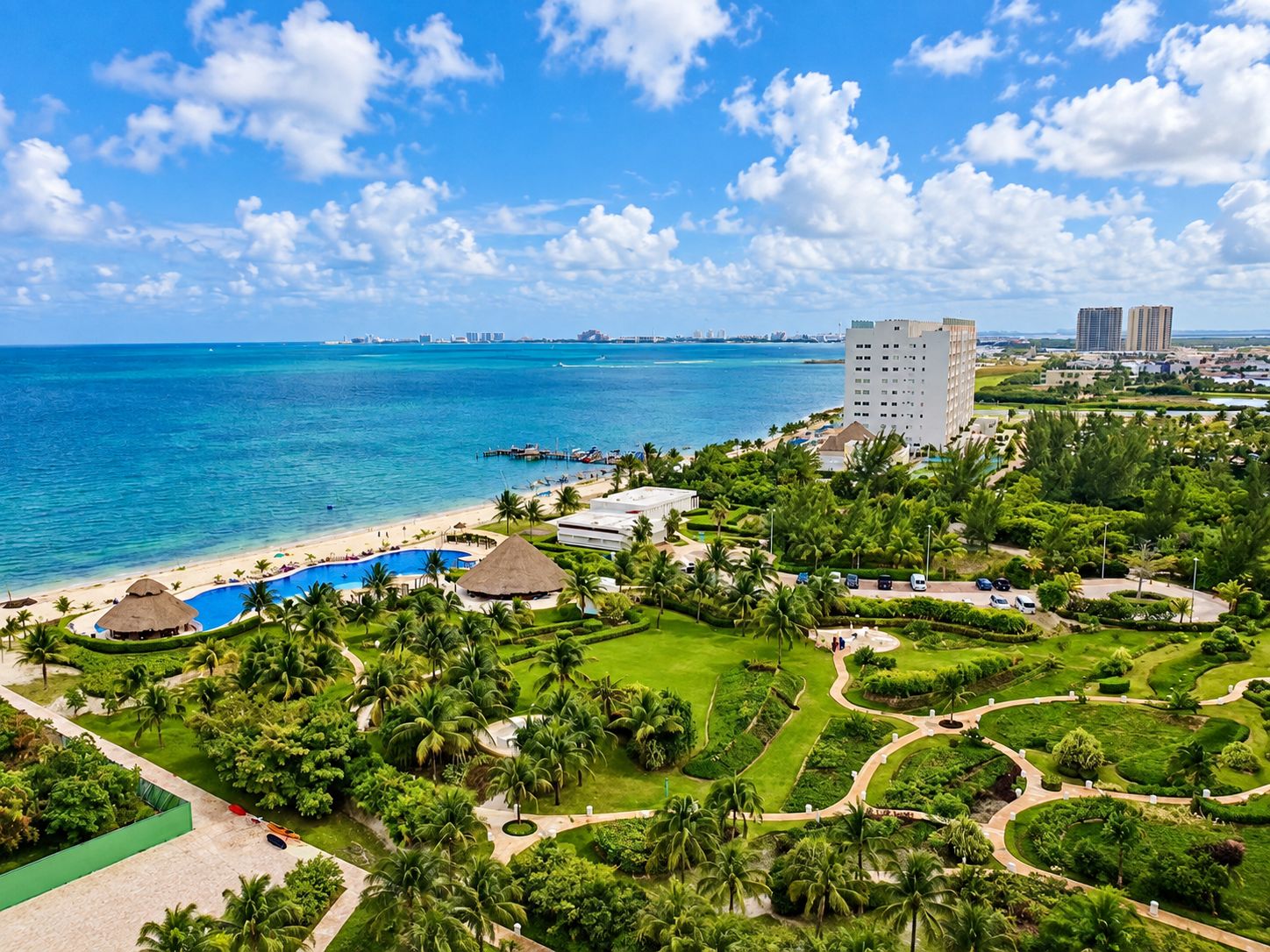 A resort with a pool, palm trees, and a view of the ocean.