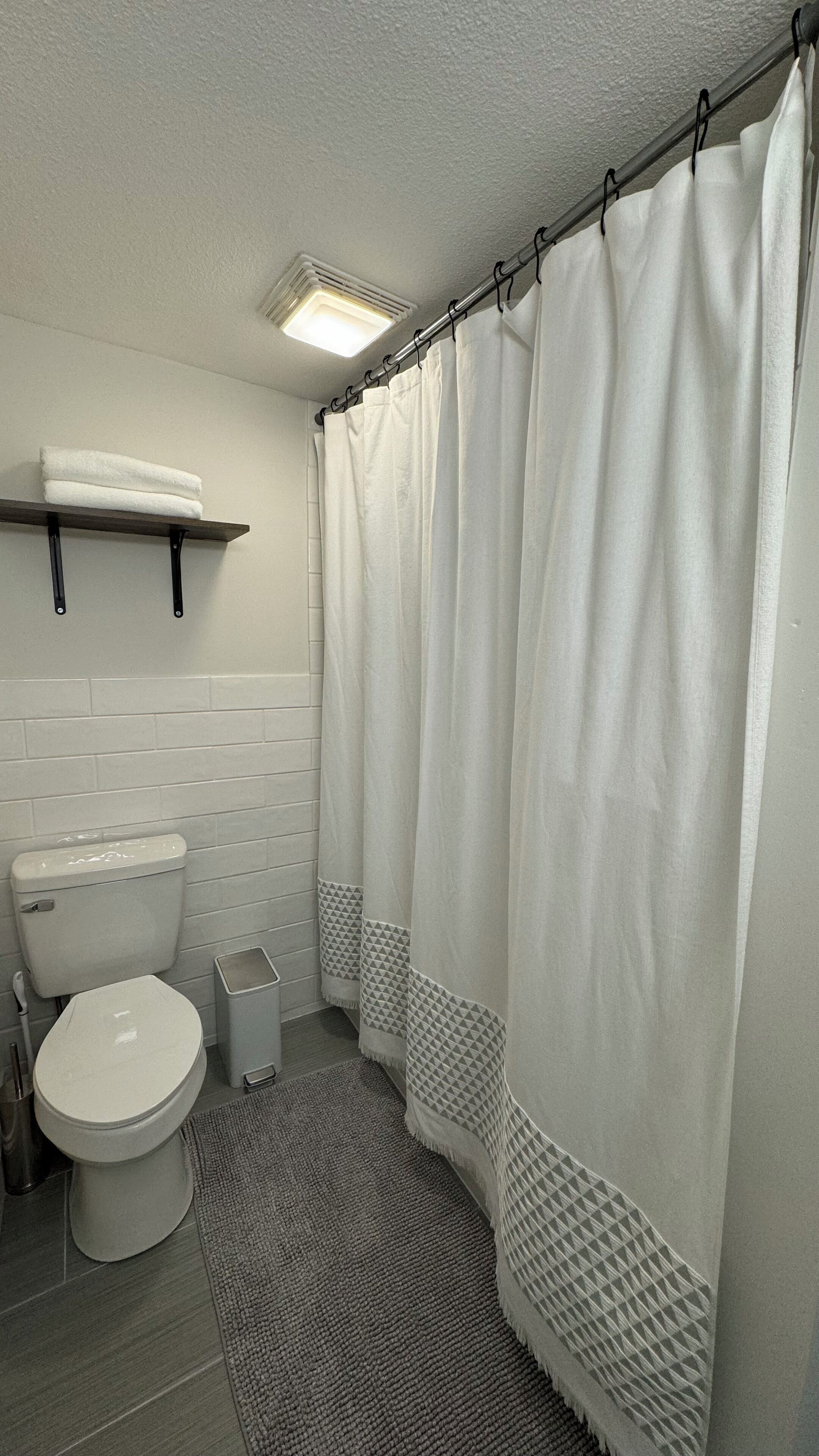 A bathroom with a toilet, a sink, a towel rack, and a shower curtain.