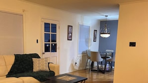 A living room with a sofa, coffee table, and patterned rug. There is a dining area with chairs and a table in the background. - Spacious 5-bedroom house in fabulous Hot Springs 1.2 miles from Oaklawn Park (Hot Springs)