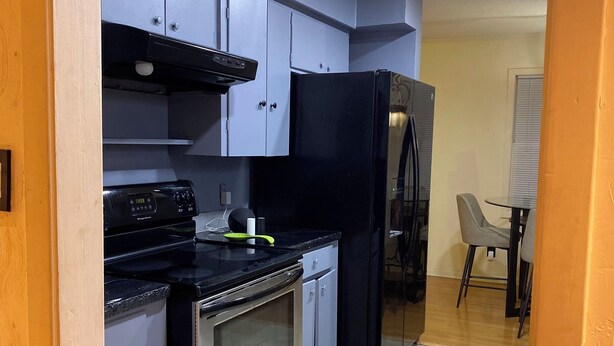 A compact kitchen with grey cabinets, a black refrigerator, and a stove. - Spacious 5-bedroom house in fabulous Hot Springs 1.2 miles from Oaklawn Park (Hot Springs)