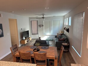 Een moderne woonkamer met een houten eettafel, banken en een televisie.