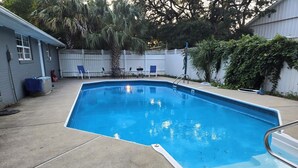 A rectangular swimming pool with a metal ladder on one side, surrounded by a concrete deck.