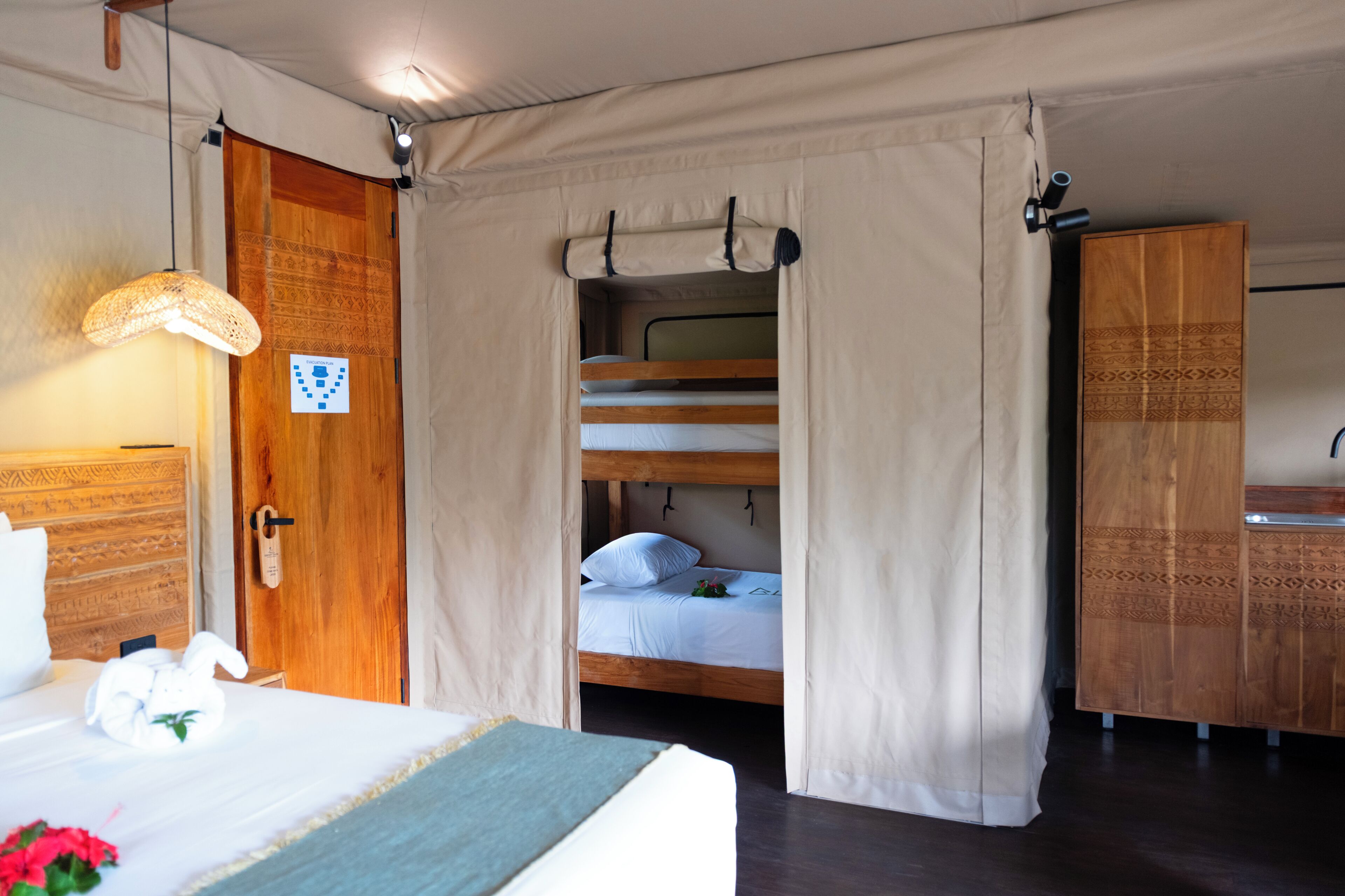 Una habitación con cama, un armario de madera, una lámpara colgante y una puerta con diseño decorativo.