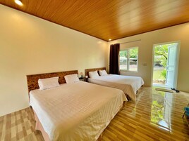 Quarto de hotel com duas camas, teto de madeira e vista para o exterior.